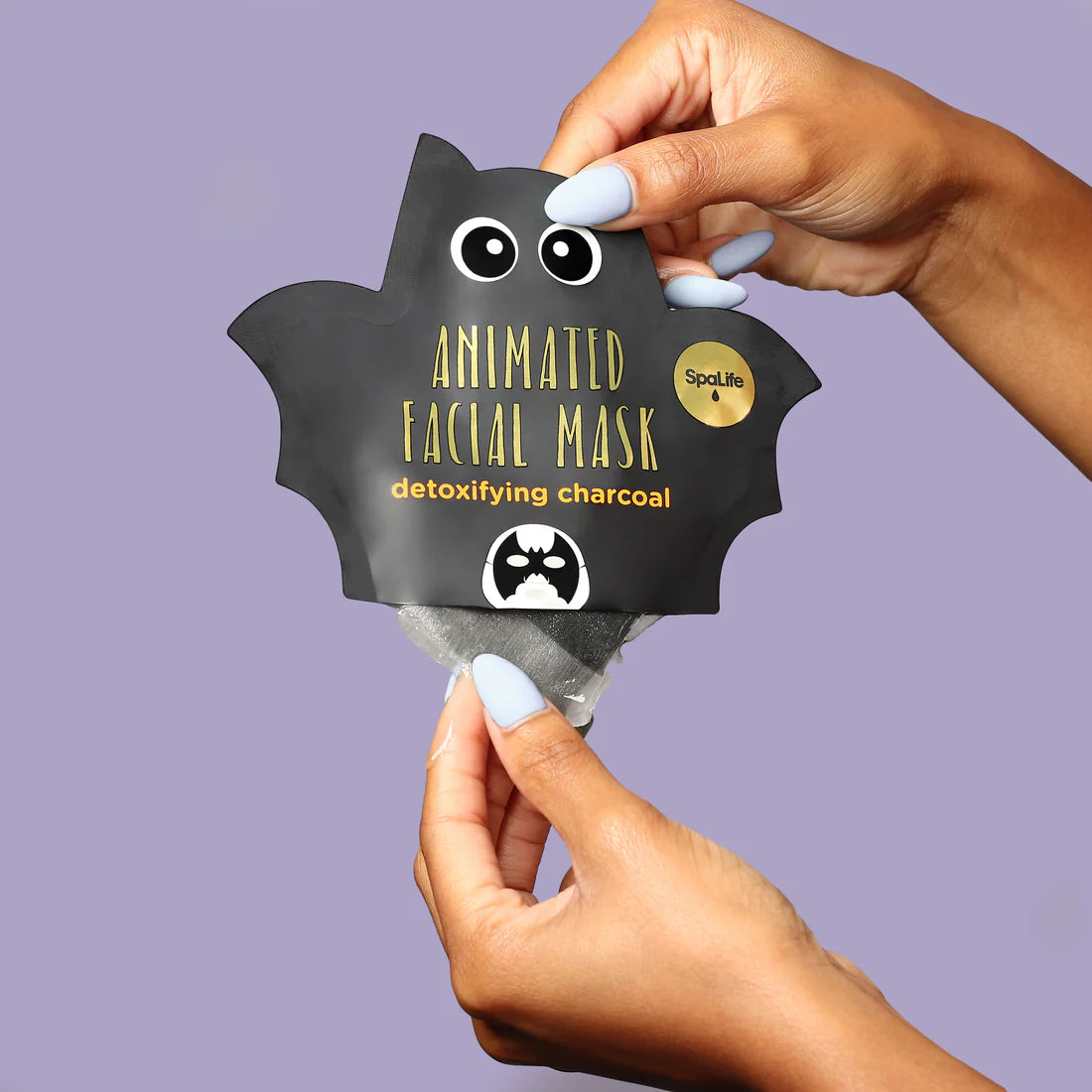 Animated bat Halloween facial mask (black) held up by hands, charcoal detoxifying