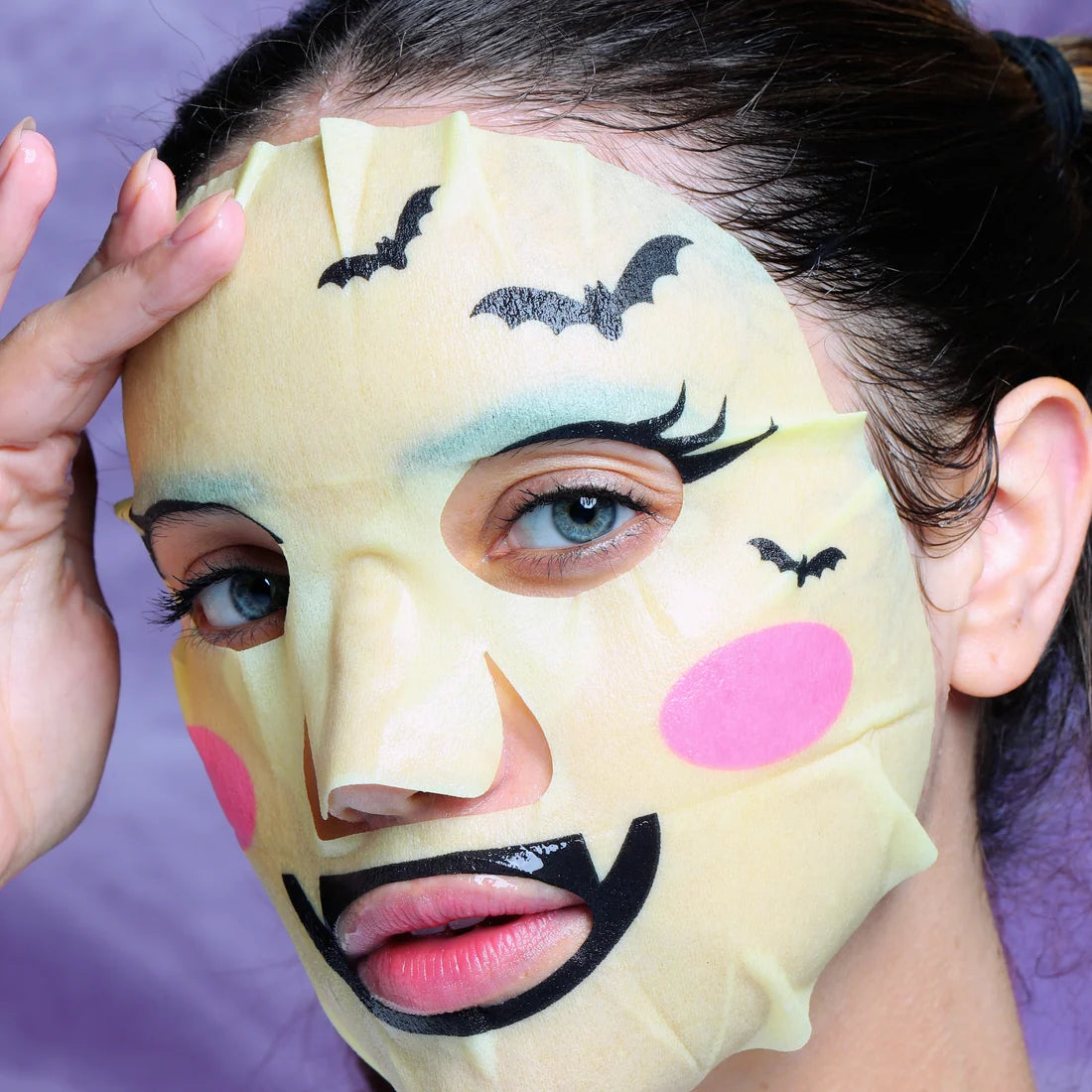 Halloween facial mask sheet with beige base, bat eye graphics and pink cheeks