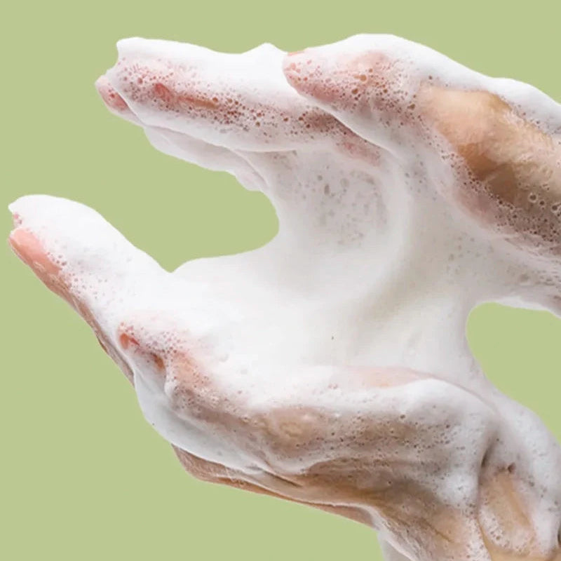 Thick white cleansing foam on fingertips, showing rich lather